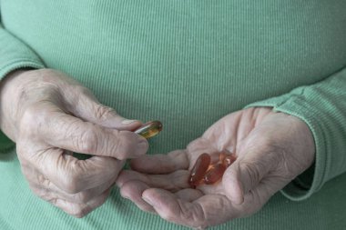 Avuç içinde vitamin hapları tutan yaşlı bir kadının elleri