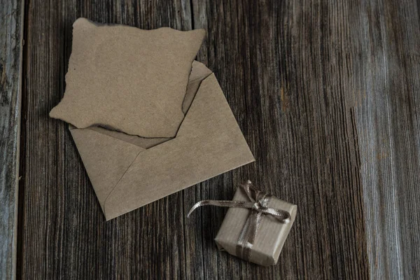 Une lettre vierge et une boîte cadeau sur une table en bois — Photo