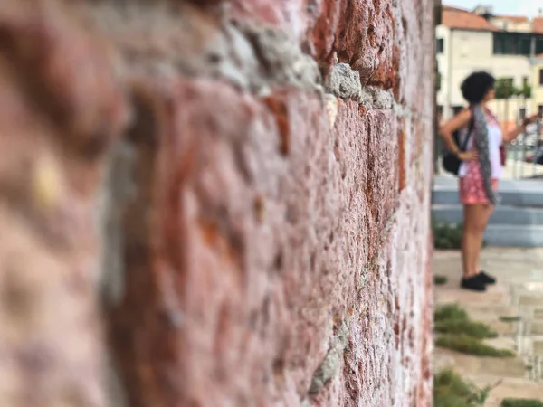 Une femme debout devant un mur de briques dans la rue — Photo