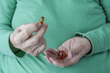 vitamin hapları tutan üst düzey bir kişinin kırışık elleri