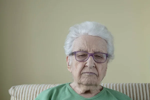 A sad senior woman wearing eyeglasses