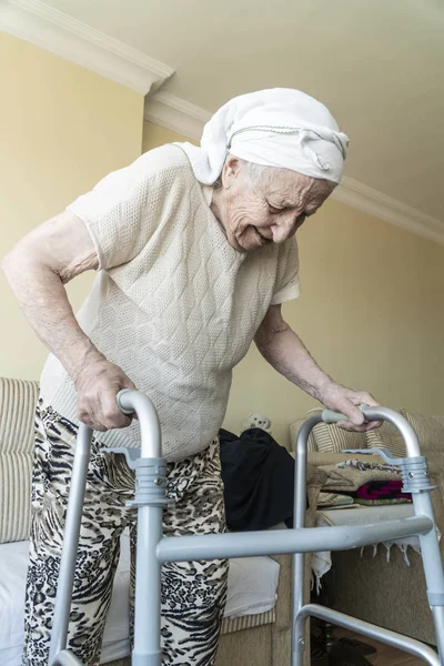 Uma mulher idosa de pé com um caminhante em casa — Fotografia de Stock