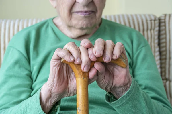 Manos arrugadas de una persona mayor sosteniendo un bastón — Foto de Stock