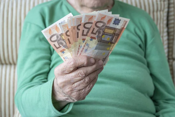 Морщинистая рука пожилой женщины, держащей банкноты евро — стоковое фото