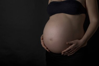 kopya alanı ile siyah arka plan üzerinde hamile kadının göbek