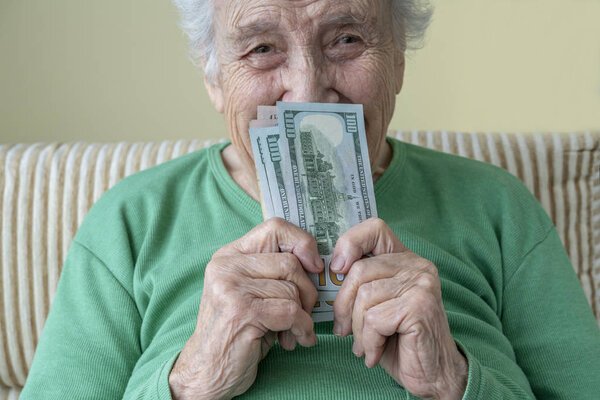 a happy senior woman holding american dollars