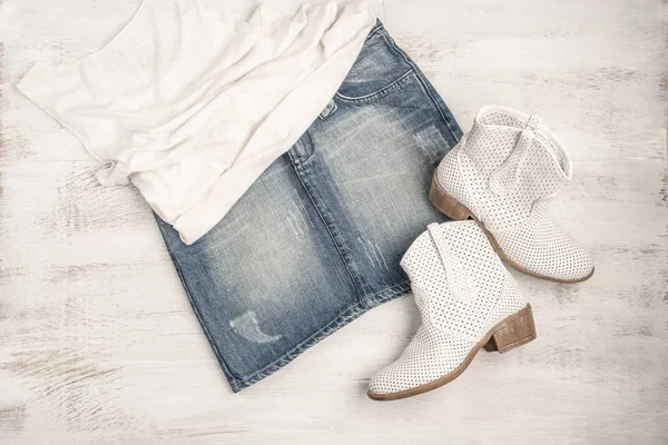 Botas blancas de moda y falda de jean en una madera — Foto de Stock