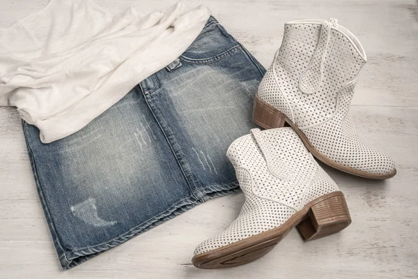 Botas blancas de moda y falda de jean en una madera — Foto de Stock