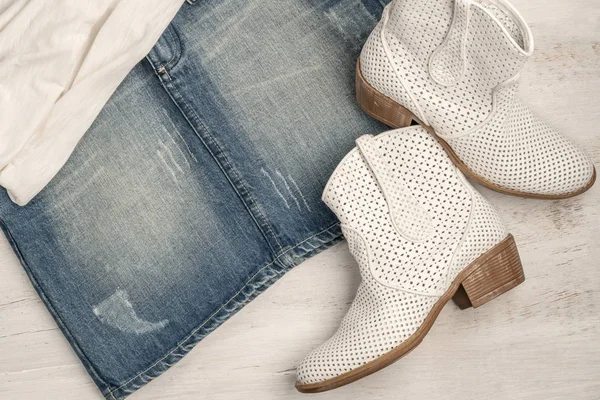 Botas blancas de moda y falda de jean en una madera — Foto de Stock