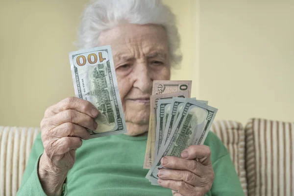 A senior woman looking to American Dollars in her hand — Stock Photo, Image
