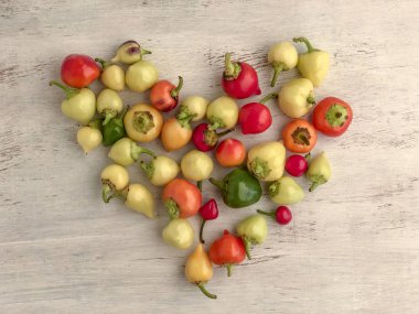 Kalp şekli ahşap masada taze biberlerle renklendirilmiş.