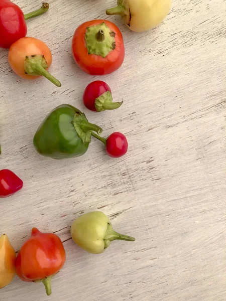 Pimentas frescas coloridas em uma mesa de madeira — Fotografia de Stock