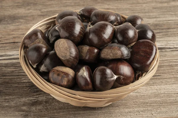 Rauwe kastanjes in mand op een houten tafel — Stockfoto