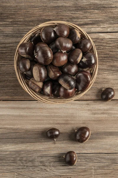 Rauwe kastanjes in mand op een houten tafel — Stockfoto