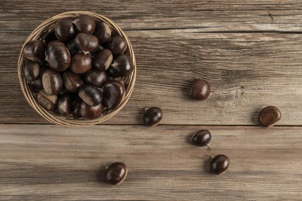 Rauwe kastanjes in mand op een houten tafel — Stockfoto