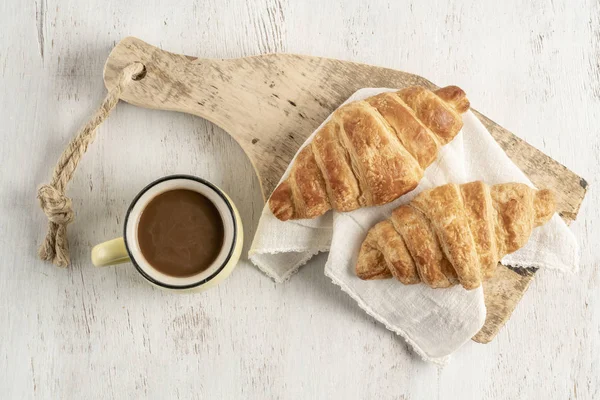 Croissant croccante e tazza di caffè su un tavolo di legno — Foto Stock