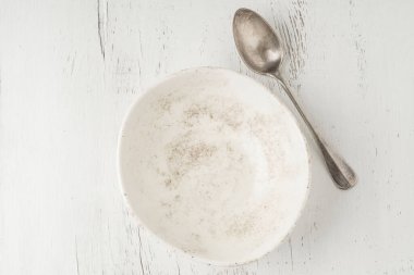 boş ve temiz bir seramik kase ve kaşık bir masada.