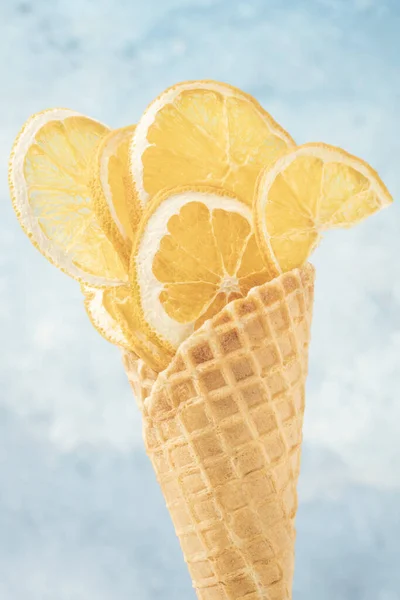 将干柑橘类水果片放在蓝色背景的华夫饼冰淇淋蛋筒中 并留有复制空间 — 图库照片