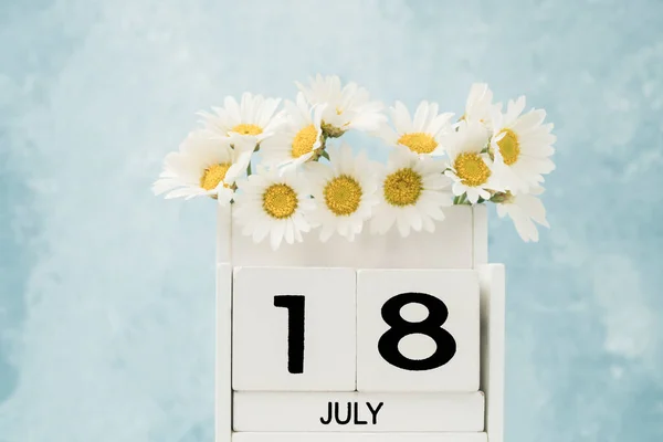 7月のホワイトキューブカレンダーは コピースペースと青の上にデイジーの花で飾られました — ストック写真