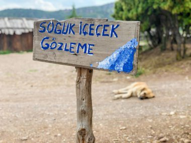 Tahta panoda soğuk içecek ve Türkçe pide yazılı.