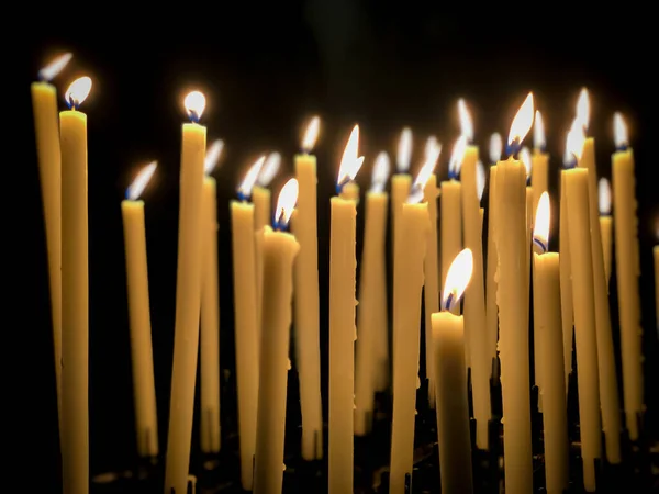 burning candle sticks over black with copy space in a church