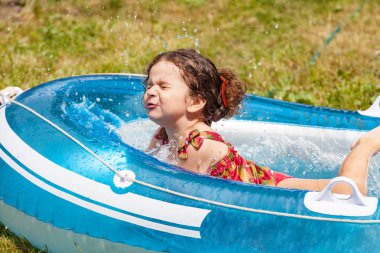 Su dolu bir şişme bota oynayan kız bebek