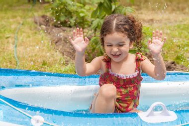 Su dolu bir şişme bota oynayan kız bebek