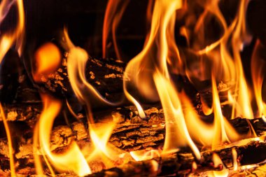 Şöminede yakacak odun, yakın çekim, ateş ve alevin dokusu, karanlık arka plan.