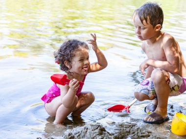 Erkek ve kız kardeş kardeşi komik bir hikaye anlatır sahilde, kum ile oynamak
