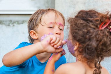 Erkek ve bir kız yüz ve vücut açık havada boyaları ile oynarken