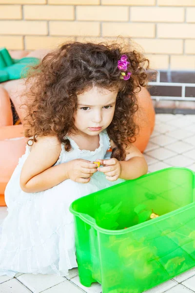 悲伤的女孩坐在一个盒子旁边的玩具户外 — 图库照片