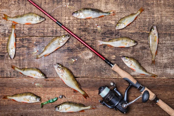 Çubuk ile makara iplik, yem ve bas balık ahşap arka planda, üstten görünüm