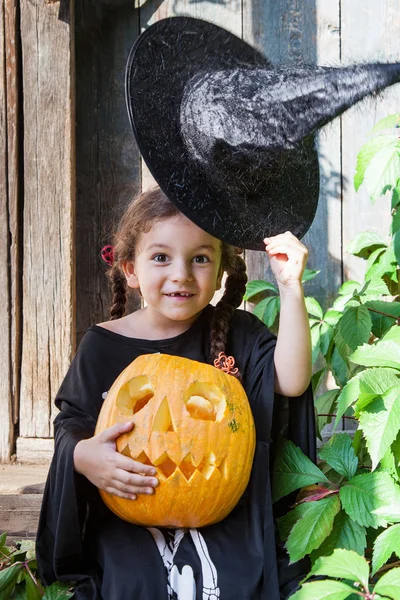 Cadılar Bayramı ve kutlama kavramı. Güzel çocuk kız cadı kostüm Cadılar Bayramı Balkabağı açık havada tutar