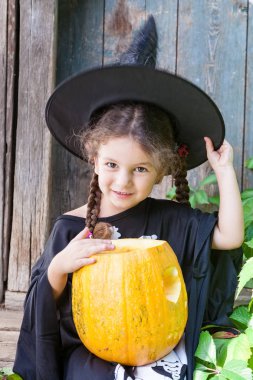 Cadılar Bayramı ve kutlama kavramı. Güzel çocuk kız cadı kostüm Cadılar Bayramı Balkabağı açık havada tutar