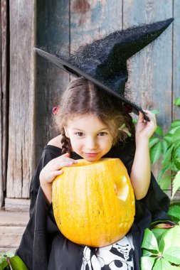 Cadılar Bayramı ve kutlama kavramı. Güzel çocuk kız cadı kostüm Cadılar Bayramı Balkabağı açık havada tutar