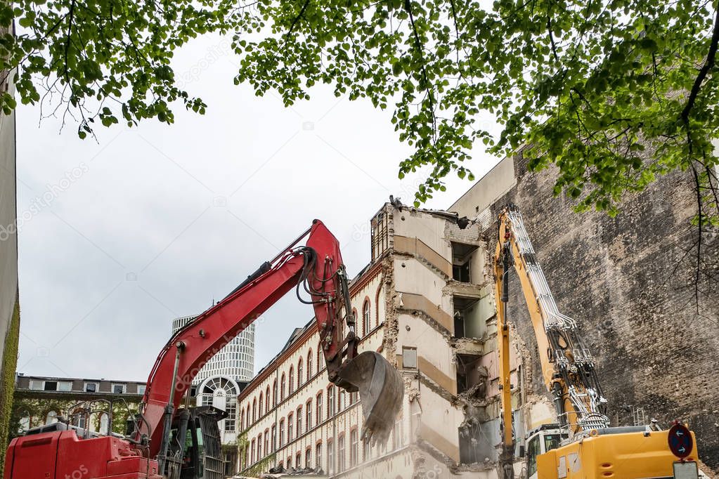Digger demolishing houses for reconstruction in Berlin, Germany. Destruction of the walls of the old building and the cleaning of construction debris with bucket of an excavator