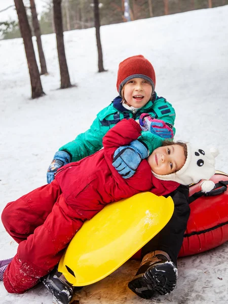 男の子と女の子のチューブそり 屋外の丘の上を滑る丘 冬のゲームおよび楽しみを下ると冬の日 — ストック写真