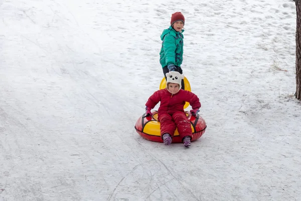 Broer Trekt Zus Buizen Sleeën Heuvel Buitenshuis Winterdag Winterspelen Plezier — Stockfoto