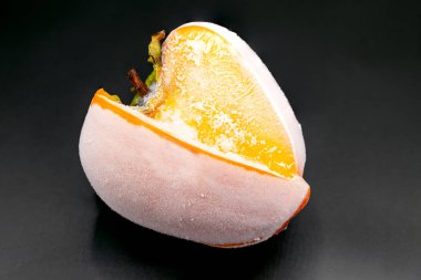 Frost'un üzerinde siyah arka plan yakın çekim ile kaplı donmuş Trabzon hurması kesmek