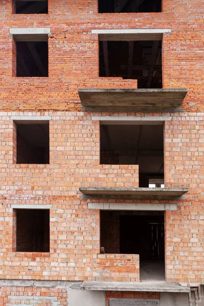 Незаконченное кирпичное здание с большим количеством окон и балконов — стоковое фото