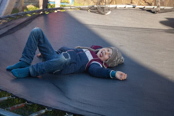 Garçon se couche sur un trampoline et sourit — Photo