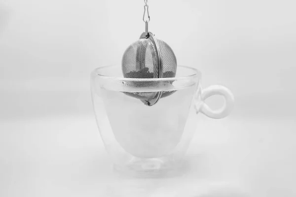 Čajový filtr s čajovým listím, který spadl do skleněného kelímku — Stock fotografie