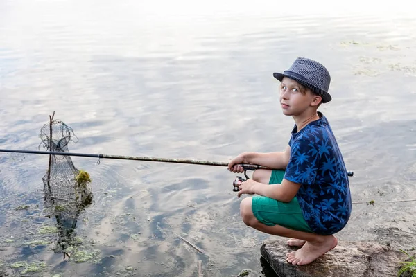 Niño con una caña de pescar atrapa un pez — Foto de Stock