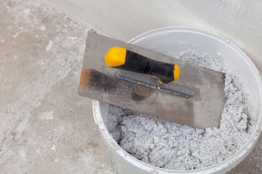 Dekoratif mineral alçıyla dolu bir kovada Spatula kullanıma hazır