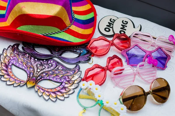 Photo booth props including funny glasses, masks, signs, and colorful hats.