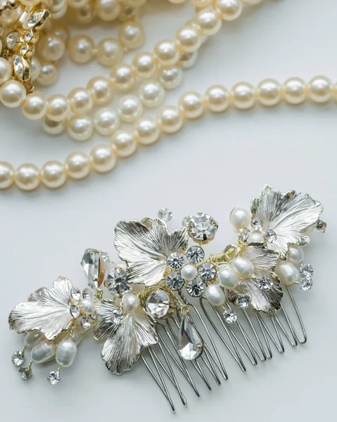 Close up of bridal jewelry detail hair pin with diamond embellishments and pearl necklace