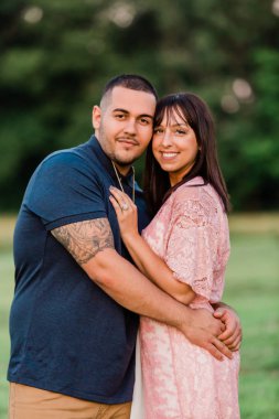 Genç Mutlu Nişanlı Çift dışarıda. Birbirine aşık ve kameraya bakan iki kişi.