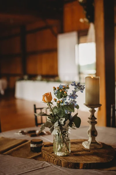 センターピースは 素朴な納屋の結婚式のレセプション会場で花の配置とキャンドルをバラ — ストック写真