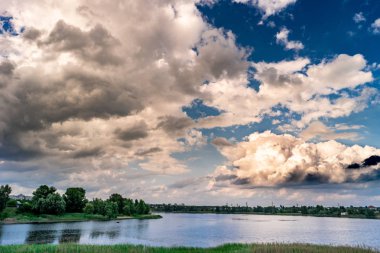 güzel göl kıyısındaki parlak mavi gökyüzü altında yeşil ağaçlar ile