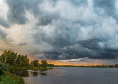 göl günbatımı sırasında üzerinde karanlık fırtınalı bulutlar